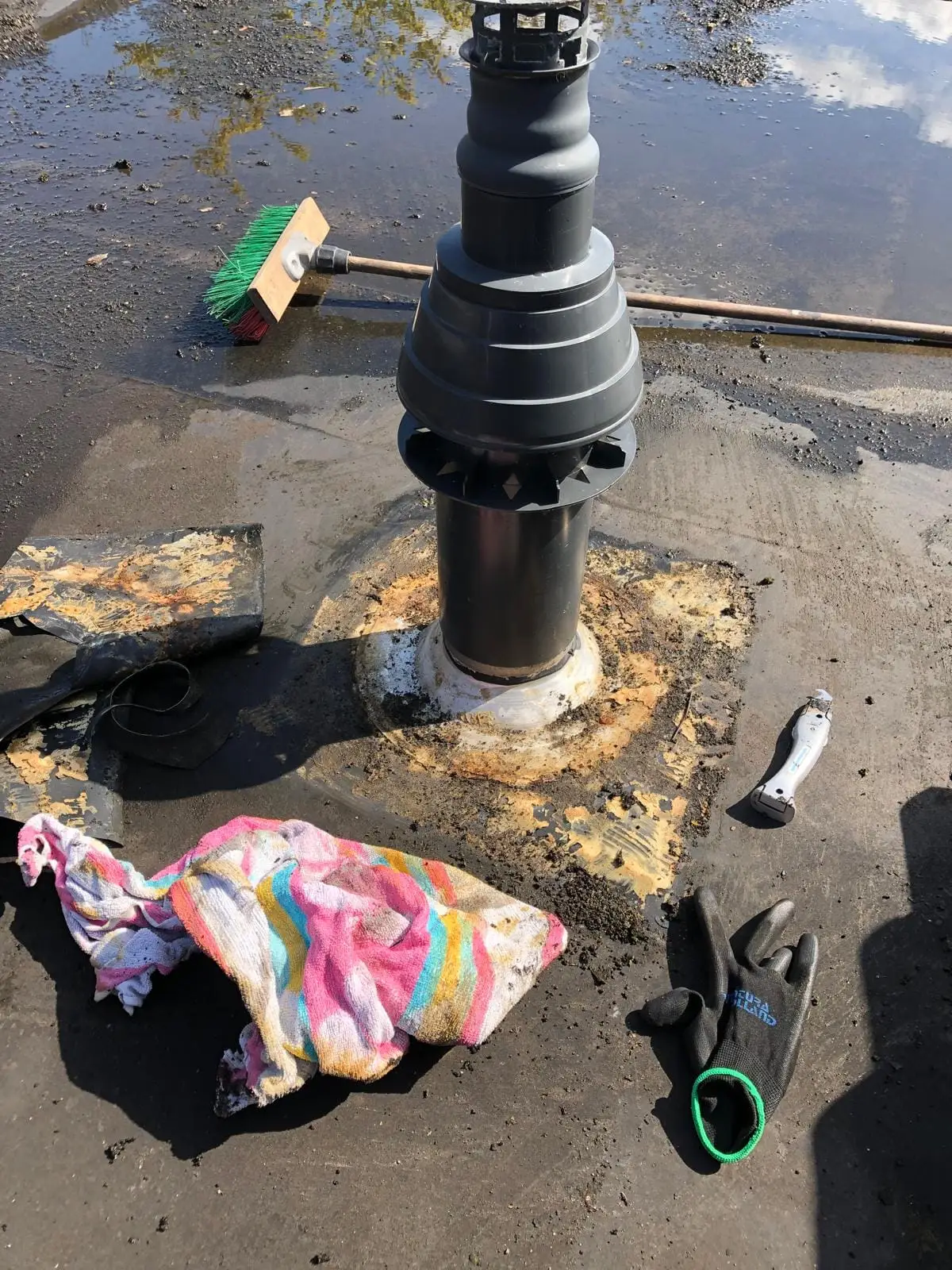 Ontluchtingspijp op een plat dak, met gereedschap rond de vers afgewerkte aansluiting